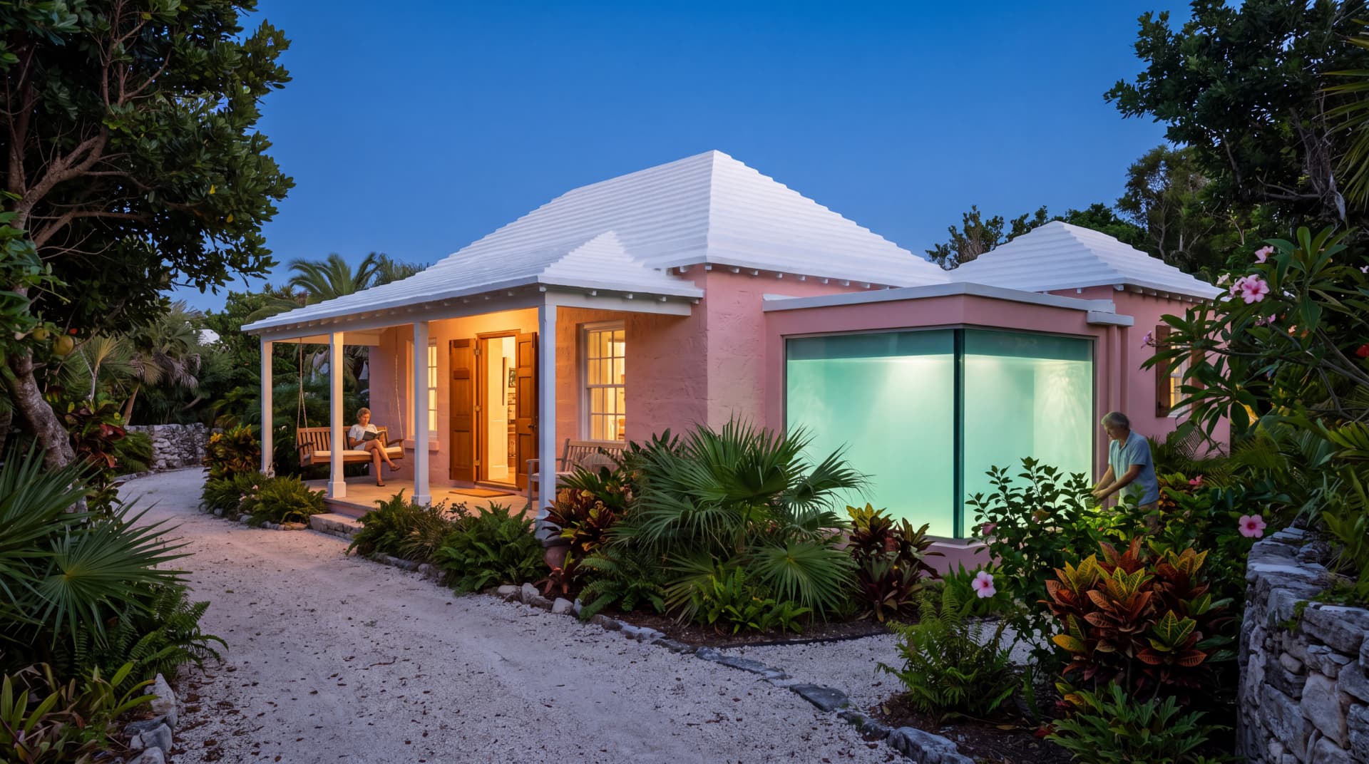 A pink Bermuda cottage at night with a large glowing cistern window revealing clear water